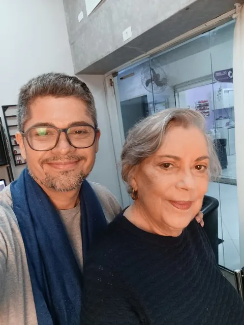 Pablo, de cachecol azul, e uma cliente de cabelos grisalhos sorriem juntos numa selfie