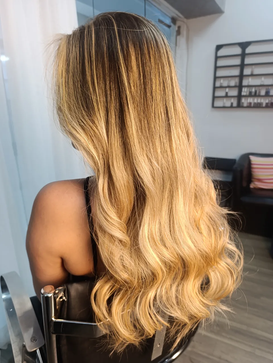 Balayage loiro com raiz natural e ondas, visto de três quartos de costas