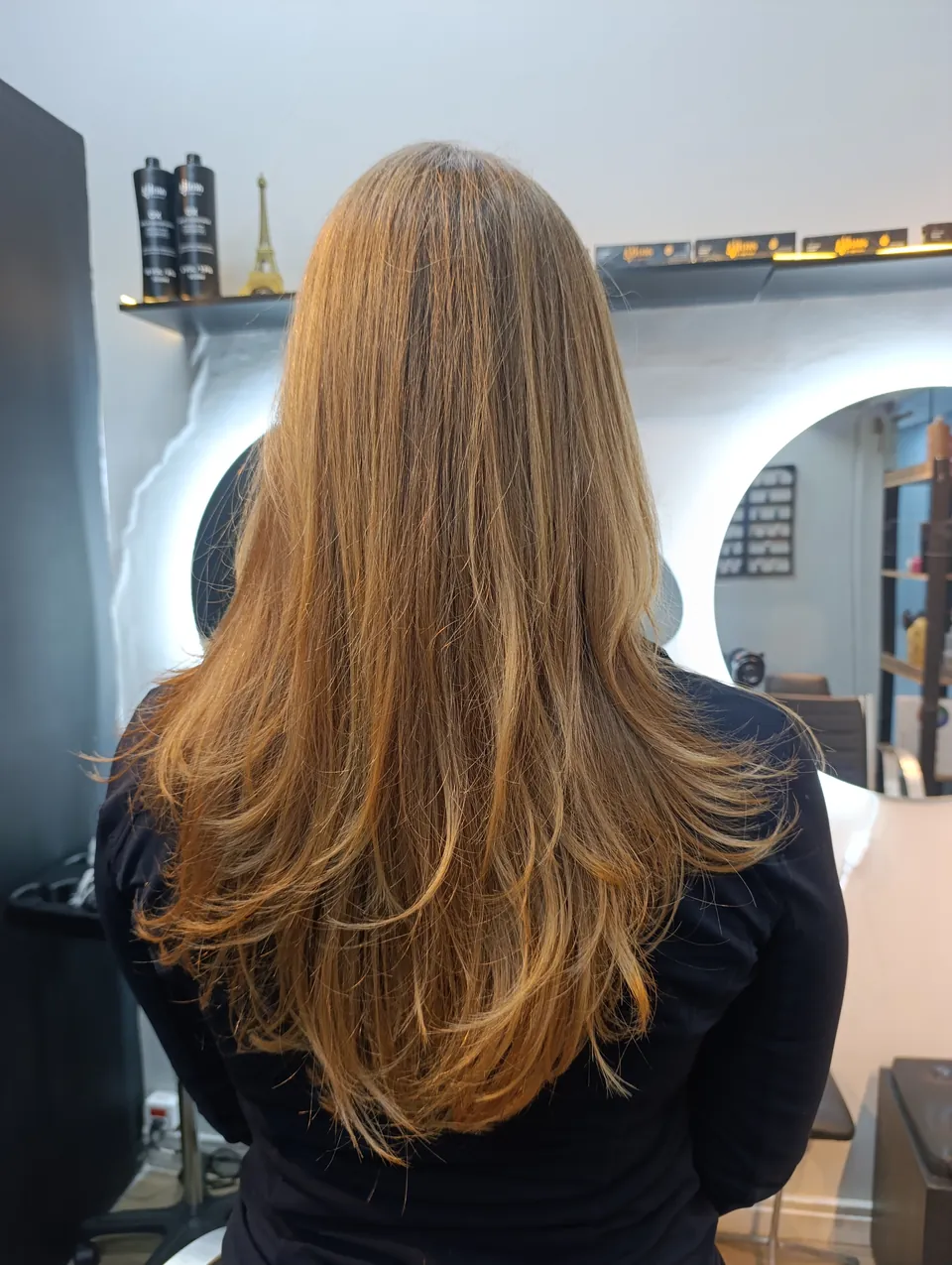 Cabelo castanho-claro com camadas e pontas iluminadas, de costas