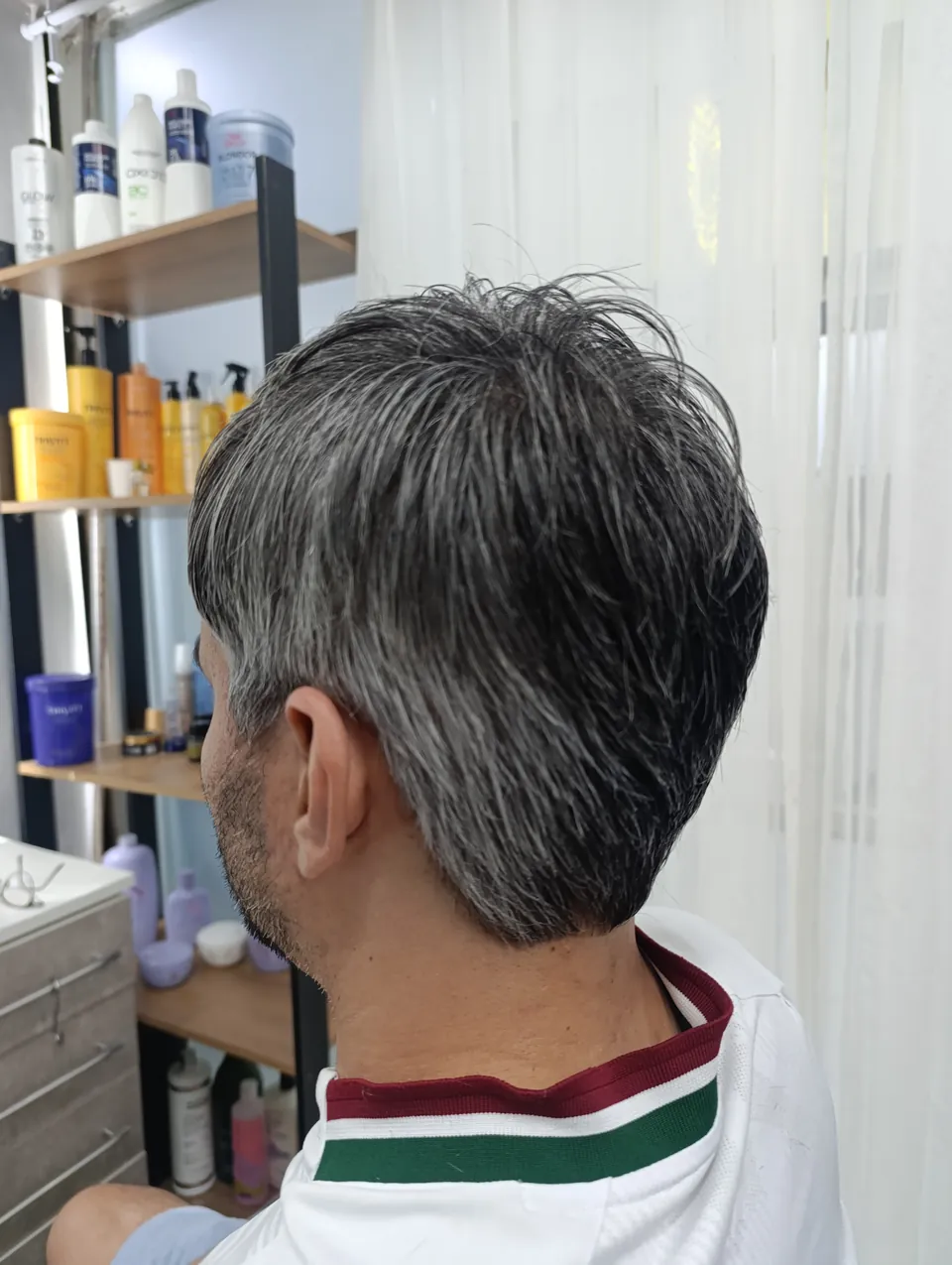 Corte masculino curto com grisalho natural, visto de lado no estúdio